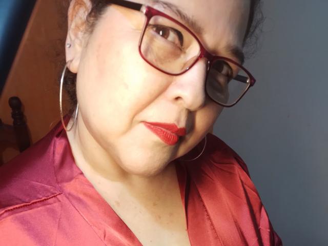 Loretta Sanchez ha il rossetto rosso, degli occhiali e una camicia rossa, e guarda di lato con un leggero sorriso. Indossa degli orecchini a cerchio e ha un piccolo piercing al naso..