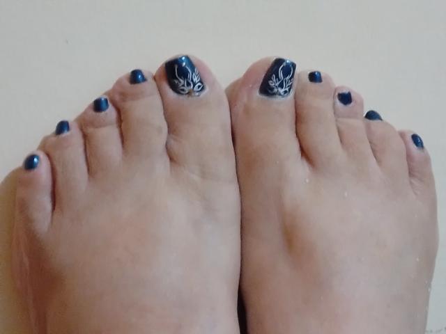 I piedi di Loretta Sanchez, con uno smalto blu scuro e disegni di foglie bianche sulle dita dei piedi grandi, sono in posizione con le piante rivolte verso l'alto..