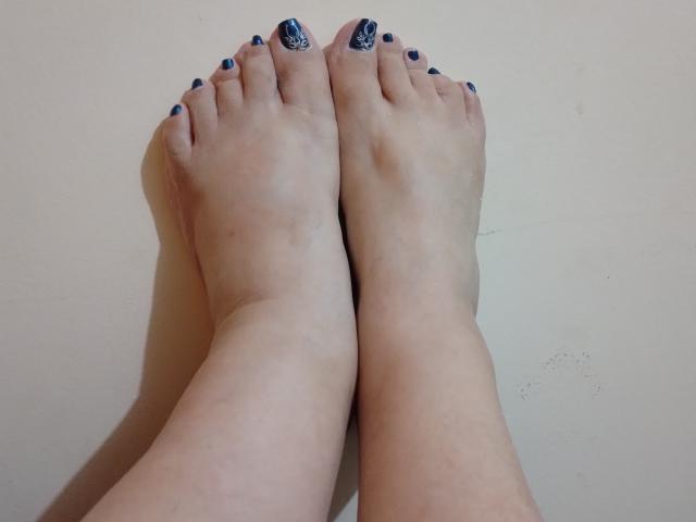 Los pies descalzos de Loretta Sanchez, con esmalte de uñas azul, y los dedos ligeramente curvados, sobre un fondo liso. Sus dedos están pintados con un diseño en espiral blanco sobre el azul..