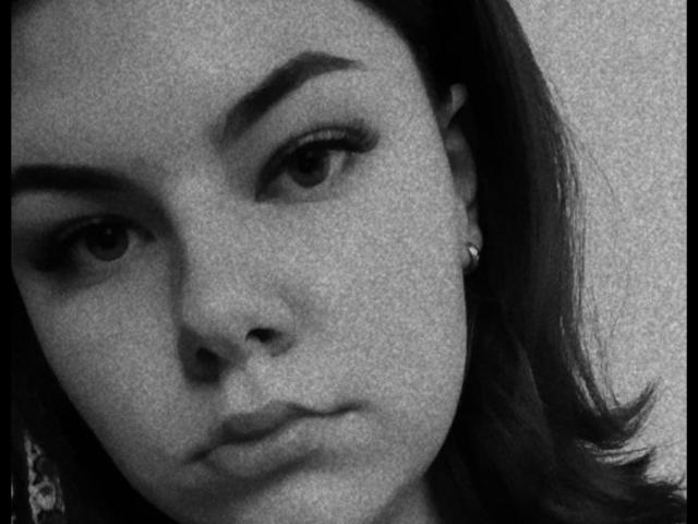 Le visage de Tina Moore sur une photo en noir et blanc, montrant ses lèvres charnues et ses sourcils légèrement arqués, avec ses cheveux foncés tombant sur la droite et de petites boucles d'oreilles visibles..