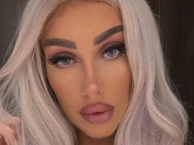 TanyaMonroe has platinum blonde hair, thick grey eyebrows, long eyelashes, and pink lips. Her blue eyes are slightly upturned, giving a seductive look. She's a hot chick.
