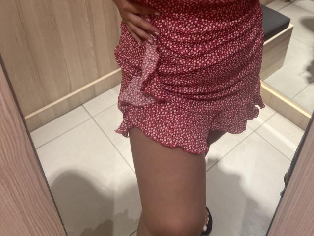 Barbarica's red, ruffled, white-dot dress, showing her bare, tan-skinned thigh and black high heel, with her hand on her hip, in a wooden, tiled room.