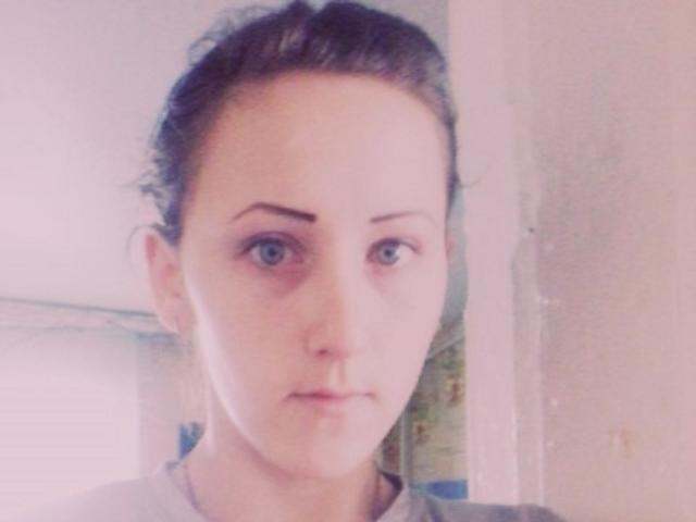 LoreneHazel tiene la piel clara, ojos azules y cabello castaño oscuro recogido, lleva una camisa gris y mira directamente a la cámara con una expresión neutra..
