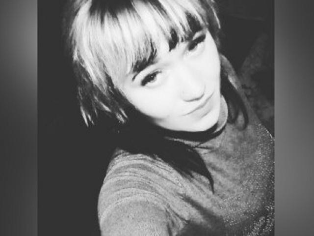 Zwart-wit selfie van HollyLaBerry met kort, blond haar met een pony, die omhoog kijkt, gekleed in een glinsterende, donkere coltrui, met een zachte uitdrukking, een licht omhoog gekeerd neusje en een zachte, lichtjes grijnzende glimlach..