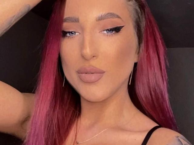 MissAlice69 tiene el pelo rosa, delineador de ojos negro al estilo "ala", lápiz labial rosa, y pechos pequeños, con un tatuaje en el brazo, lleva una correa negra y aretes de aro dorados..