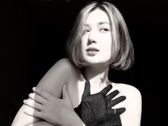 Cindy, con un taglio di capelli a caschetto, indossa un guanto nero a pois, braccia incrociate, pelle bianca e un'espressione seria, in una fotografia in bianco e nero..