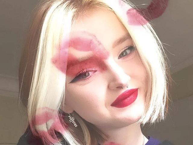 LaPochka ha i capelli biondi con riflessi rosa, eyeliner rosso e rossetto rosso. Sorride, ha un piercing al naso e indossa una maglietta nera con un orecchino d'argento..