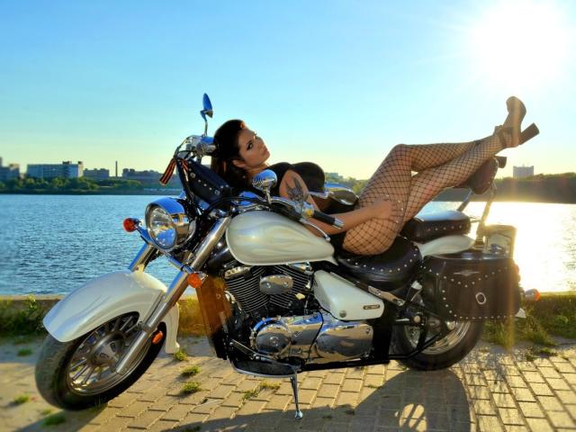 AlinaMilf with tits and ass, in fishnet stockings and heels, lounging on a white Harley, legs up, by a lake, sun setting, clear sky, motorcycle detailed, sexy.