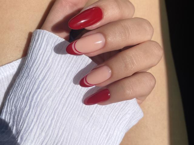 Pingli's hand with glossy red nails on the tips, pale pink nails on the rest, holding a white ribbed sleeve. Sunlight highlights her clean, manicured nails.