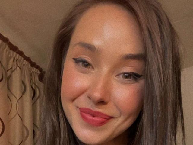LiaQuinn hat hellbraune Haut, glattes braunes Haar, grüne Augen mit schwarzem Eyeliner und roten Lippen. Sie lächelt leicht und zeigt ein süßes Gesicht. Ihre Brüste sind nicht sichtbar..