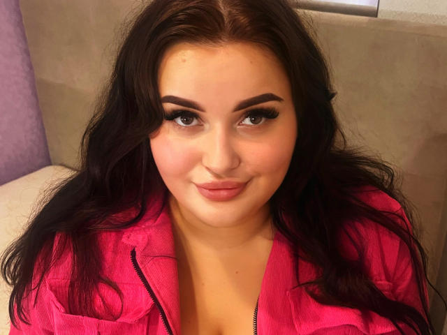MonaSteele heeft donker, golvend haar, dikke wenkbrauwen, lange wimpers en draagt een roze jas. Ze heeft een schattige, lichtelijk zelfingenomen blik, met haar lippen samengeknepen..