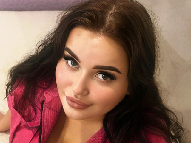 MonaSteele heeft donker, golvend haar, dikke wenkbrauwen, lange zwarte wimpers en een subtiele glimlach. Ze draagt een roze shirt, waarbij haar borsten gedeeltelijk zichtbaar zijn. Haar huid is licht..