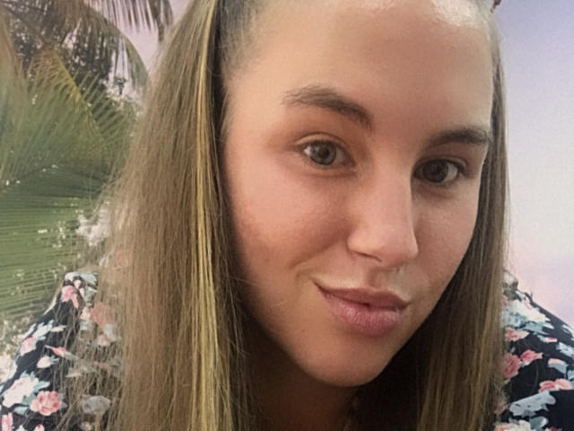 Dooris heeft een lichtbruine huid, steil bruin haar met blonde highlights, en ze glimlacht met lichtroze lippen. Ze draagt een bloesemtop. Haar borsten zijn niet zichtbaar..