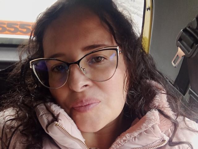 HannahKissForU steht mit verschränkten Knöcheln vor einer roten Wand. Ihre Fußnägel sind rosa lackiert. Ihre Haut ist hell, und ihre Zehen sind leicht nach oben gerichtet..
