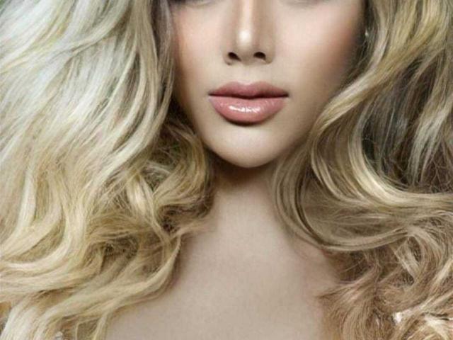 Het gezicht van GilinurDreams, met blond, golvend haar, volle, roze lippen en subtiele make-up. Haar gladde huid en zachte uitdrukking staan centraal in de foto. Borsten niet zichtbaar..
