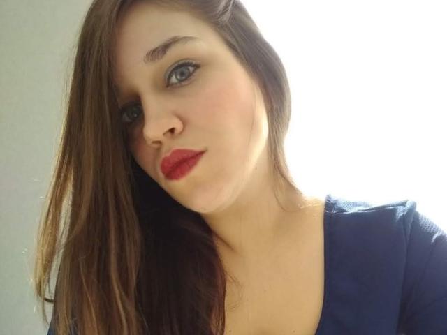 Faroles heeft blauwe ogen, rode lippenstift en lang bruin haar. Ze draagt een blauw topje, met een licht geopende mond en een zachte, zelfverzekerde uitdrukking..