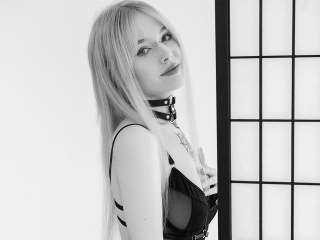 LaneyvilI a de longs cheveux blonds, du fard à paupières noir, un collier en cuir noir et un soutien-gorge en dentelle noire. Elle regarde l'appareil photo avec un léger sourire, montrant ses seins..