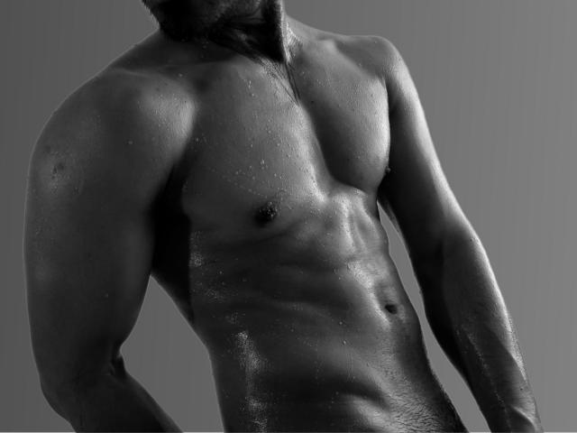 O torso brilhante, molhado e musculoso de Stefanoeverett, em preto e branco, com abdominais definidos, pequenos mamilos e gotas de água na pele escura e brilhante. Seu braço e peito estão ligeiramente virados..