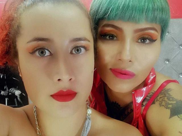 AbbyElecktra with red lipstick, green bob, and red vinyl top, next to AbbyElecktra with curly red hair, red eyeliner, and red lipstick, showing tattoos.