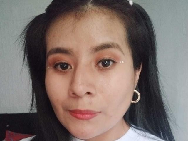 PaquitaHot hat eine hellbraune Haut, schwarze Zöpfe, kleine silberne Punkte als Eyeliner, roten Lippenstift und einen silbernen Ohrring in Form eines Reifens in ihrem rechten Ohr. Ihre Augenbrauen sind leicht buschig..