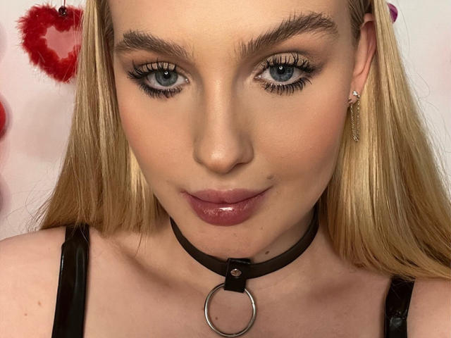 OliviaBent heeft blond haar, blauwe ogen en glanzende, roze lippen. Ze draagt een zwarte leren choker met een ring en heeft lange wimpers. Haar borsten zijn zichtbaar met zwarte bandjes..
