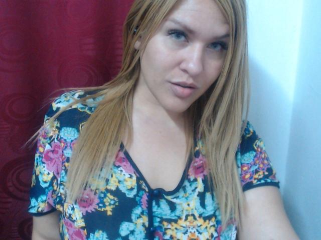 BigDirtyBoobs69 has light skin, straight blonde hair, and is wearing a colorful floral shirt. She's looking at the camera with a slightly open mouth.