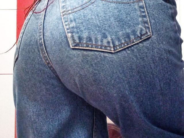 Les fesses de Zanoza sont mises en valeur par un jean bleu denim ajusté, révélant un galbe légèrement incurvé et une poche arrière visible. Son jean est légèrement usé, ce qui met en évidence sa texture et son élasticité..