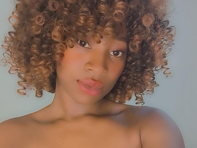 Brielle69 has curly brown hair, light brown skin, and pinkish lips, with a small nose piercing and no clothes visible. Her expression is slightly pouty.