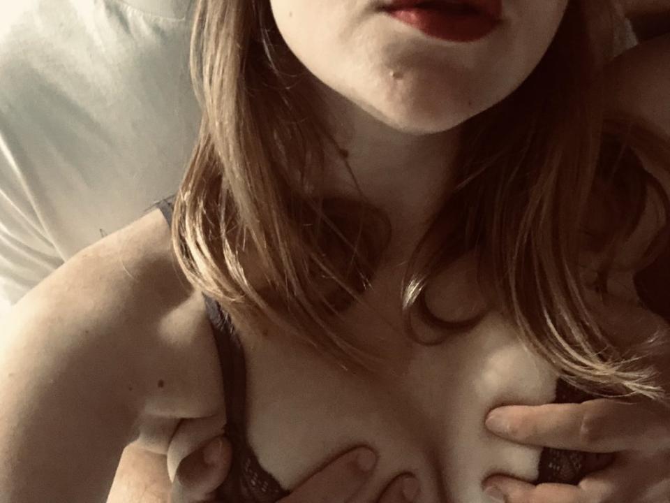 NicholasAndErika's tits, held by her own hands, in a lacy black bra, with her red lips slightly parted, and her blonde hair falling to the side.