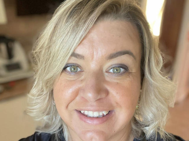 BlueMaryAnne tiene el cabello rubio y ondulado, ojos verdes y una cara sonriente con dientes blancos. Lleva una blusa negra y pequeños aretes. Su piel es clara y es atractiva..