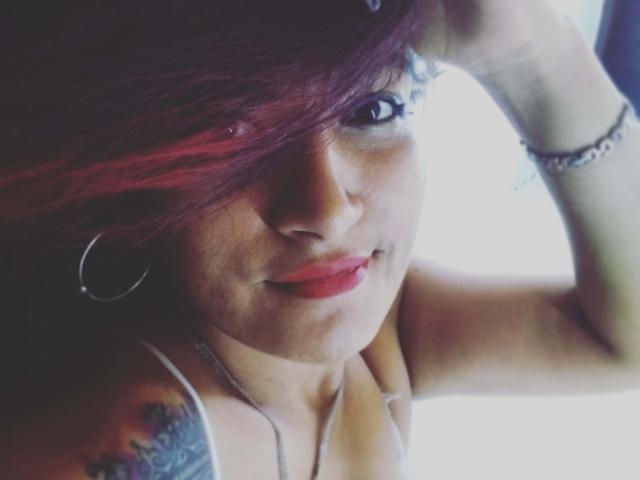CoffeCream tiene el pelo rojo, aros grandes y un tatuaje en el hombro. Lleva lápiz labial rojo, un collar de plata y una pulsera, y tiene una expresión ligeramente altanera..