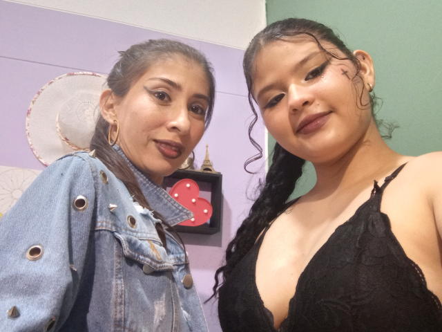 AngelaAndBarbara, zwei lateinamerikanische Frauen mit dunklem Haar, die Jeans und schwarze Spitze tragen, zeigen ihre Brüste in einem Selfie, lächeln, tragen Creolen und Lippenstift..