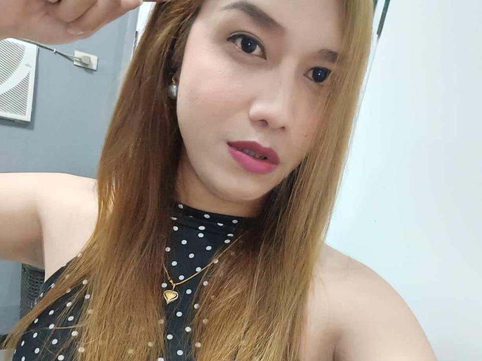LuckyStar mit langen blonden Haaren, pinkem Lippenstift, einem schwarzen Top mit Punkten, einer goldenen Halskette und Perlenohrringen, die ihr süßes Gesicht und ihre kleinen Brüste in einem Selfie zeigen..