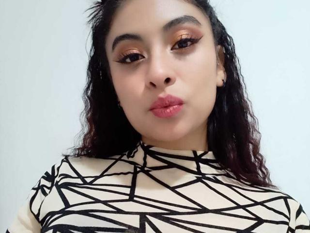 Samantha Smith ha i capelli ricci e scuri, gli occhi marroni e le labbra rosa. Indossa una maglietta a righe nere e bianche con un motivo geometrico e guarda direttamente la fotocamera con un leggero sbuffo..