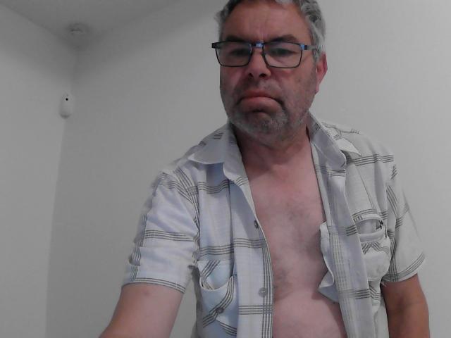 Un Jedi di mezza età con capelli grigi, occhiali e barba, che indossa una camicia bianca a quadri aperta, che lascia scoperto il petto e l'addome. La sua camicia è sbottonata, mostrando il suo petto nudo..