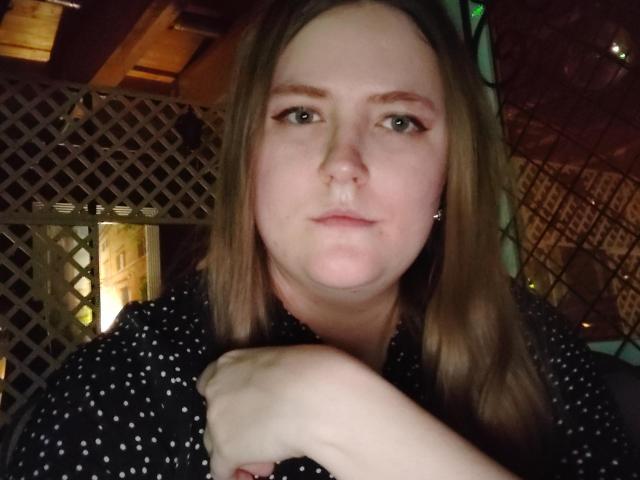 Melissa Fine, con un naso leggermente gonfio, capelli castano chiaro e una camicia nera a pois, ha le braccia incrociate e appare seria in un ambiente in legno, scarsamente illuminato..