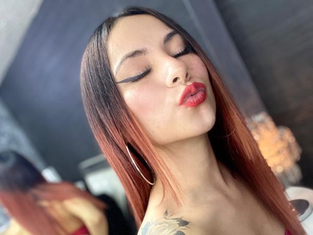 ValeryHarllow heeft rood gekleurd, steil haar, gesloten ogen, rode lippenstift en een tatoeage op haar rechter schouder. Ze frumelt met haar volle lippen en draagt grote oorringen..