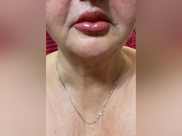 PeggySoft's glossy red lips, slight double chin, and silver necklace on her neck. Her skin has some freckles, and she's wearing a red shirt. Boobless in this shot.