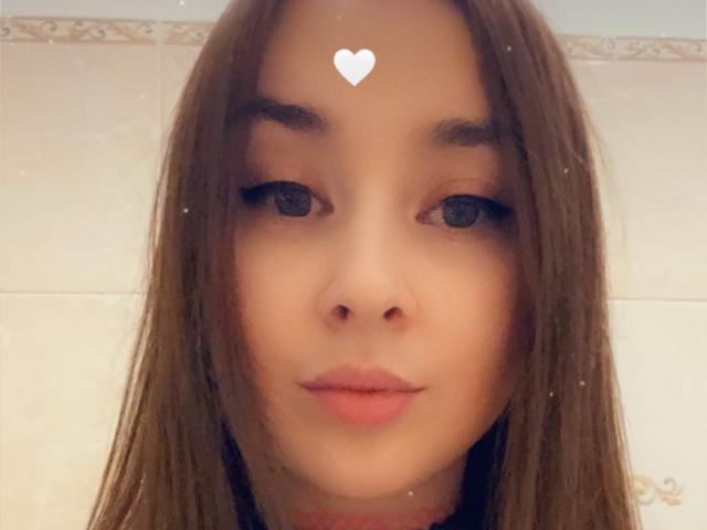 HentaiShing69 tem cabelo castanho, olhos azuis e um adesivo em forma de coração na testa. Seus lábios rosados estão levemente franzidos. Ela está usando uma maquiagem discreta. Seu nariz é pequeno e fofo..