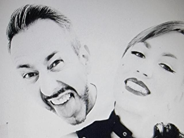 Autoportrait en noir et blanc de TuttiFloyd69, avec un adulte souriant à gauche et un tout-petit avec la langue tirée à droite, tous deux regardant la caméra..