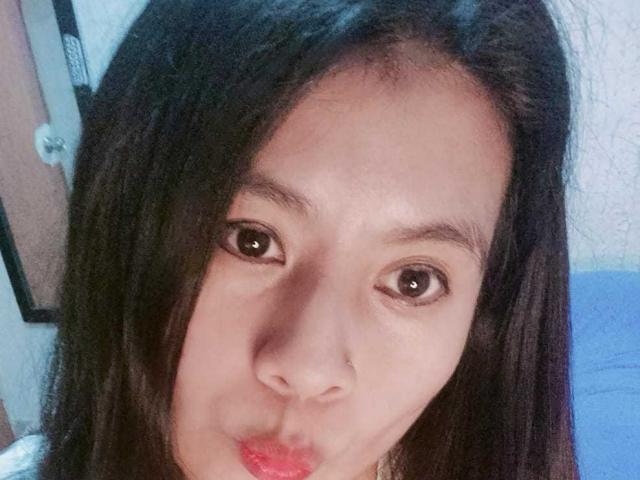 PaquitaHot, com cabelo preto e liso, olhos castanhos e lábios vermelhos levemente curvados, fazendo uma carinha fofa e com os lábios cheios em uma selfie. Ela tem um nariz pequeno e um rosto muito bonito..