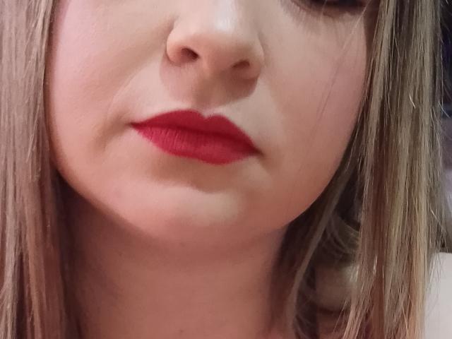 El rostro de NatalyHami, mostrando una piel pálida, lápiz labial rojo y cabello castaño liso, con la nariz y el labio superior en primer plano, labios rojos ligeramente entreabiertos y una expresión neutra..