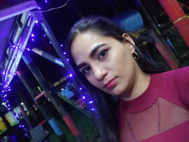 AfroditaHan with dark hair, red mesh top, hoop earrings, and subtle makeup, looking at the camera, surrounded by blue fairy lights, night setting.