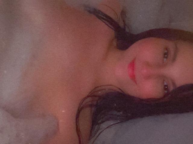 EstefaniaRamos: Heet in een bubbelbad, nat donker haar, rode lipstick, zacht lachend, topless met water en bubbels die haar borsten bedekken, achterover liggend, huid licht glanzend..