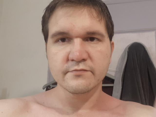 NectarineFad hat ein rundes Gesicht, kurze braune Haare und einen leichten Bart. Sein obere Körper, der oben ist, zeigt einen leicht rosafarbenen Hautton und eine kleine Brust..