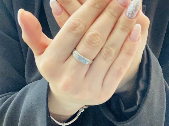 KarKutie's hands, with a diamond ring on her finger, showing off her long, glittery nails. She's wearing a black top, and her bracelet is partially visible.
