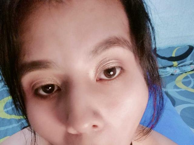 El rostro de PaquitaHot, con ojos marrones, cejas oscuras y una nariz pequeña, tiene cabello negro y un ligero tono azulado en el lado derecho. Su piel es de color marrón claro..