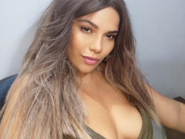 Atenaa tiene el pelo largo y ondulado, de color marrón, cejas pobladas y lápiz labial rosa. Lleva una blusa verde, de escote bajo, que deja ver sus grandes senos redondos. Su piel es morena..