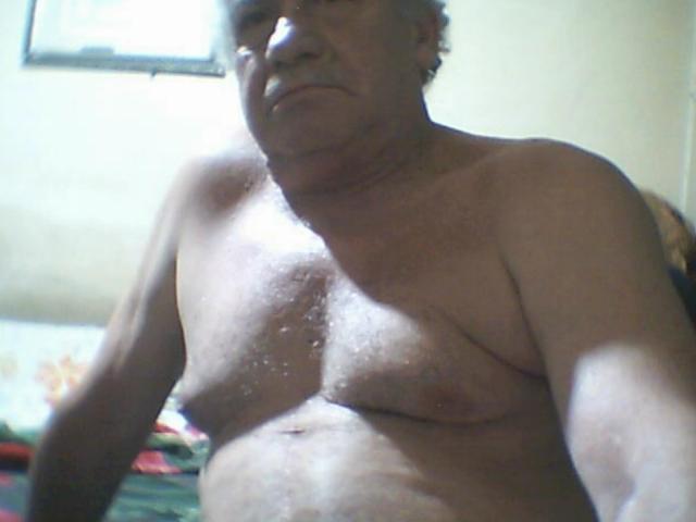 LoloWhite is a fat, shirtless, middle-aged dude with small tits and a chubby ass, showing a serious face in a low-light room. His skin is glistening with sweat.