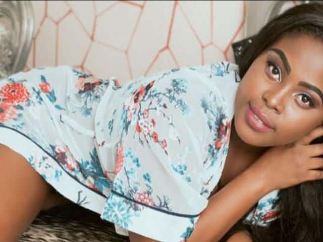 OsaLovely lying on a wicker chair, wearing a floral white dress, showing her cute brown ass, with dark brown hair and a soft smile, looking at the camera.